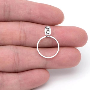 May include: A silver ring pendant with a circular design. The pendant is hanging from a silver chain.