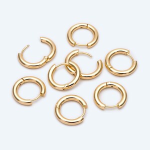 May include: Set of seven gold hoop earrings of varying sizes. The hoops are all smooth and have a shiny finish.