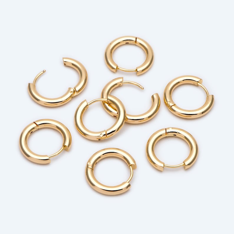 May include: Set of seven gold hoop earrings of varying sizes. The hoops are all smooth and have a shiny finish.