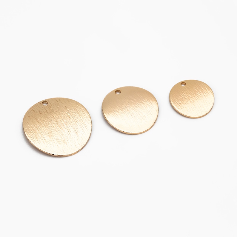 May include: Three gold-colored metal circles with a brushed finish and a small hole in the center. The circles are different sizes.