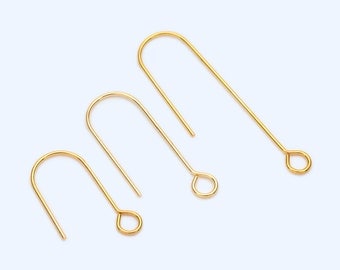 May include: Three gold-colored earring hooks of varying sizes are arranged on a light blue background. Each hook has a curved top and a loop at the bottom. The hooks are made of a shiny, metallic material.