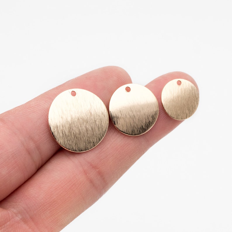 May include: Three gold-colored metal circles with a hole in the center. The circles are different sizes and have a brushed finish.