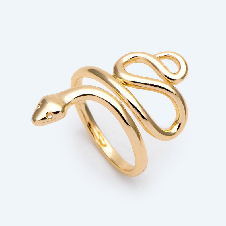 May include: A gold-coloured snake ring with a coiled design. The ring features a snake head with two small eye details. The snake's body wraps around the finger, creating a unique and stylish accessory.