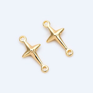 May include: Two gold-tone metal cross charms with a loop on each end. The crosses have a simple, slightly textured design.