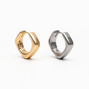 May include: A pair of square hoop earrings, one gold and one silver.