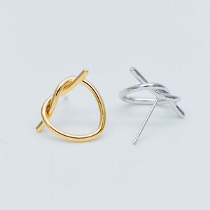 May include: A pair of minimalist earrings with a twisted knot design. One earring is gold and the other is silver.