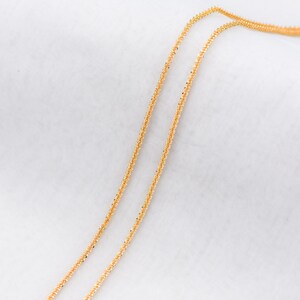 Peut inclure: Deux colliers dor&eacute;s d&eacute;licats avec un design torsad&eacute; textur&eacute;. Les cha&icirc;nes sont pr&eacute;sent&eacute;es sur un fond blanc, soulignant leurs d&eacute;tails complexes et leur teinte m&eacute;tallique chaude. Les colliers semblent l&eacute;gers et adapt&eacute;s au superposition.