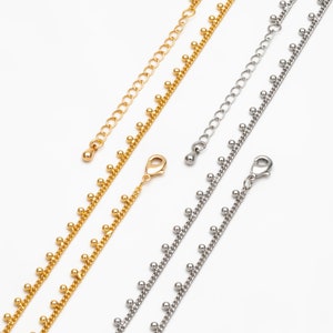 May include: Two delicate chains with small beads, one gold and one silver, with lobster claw clasps.