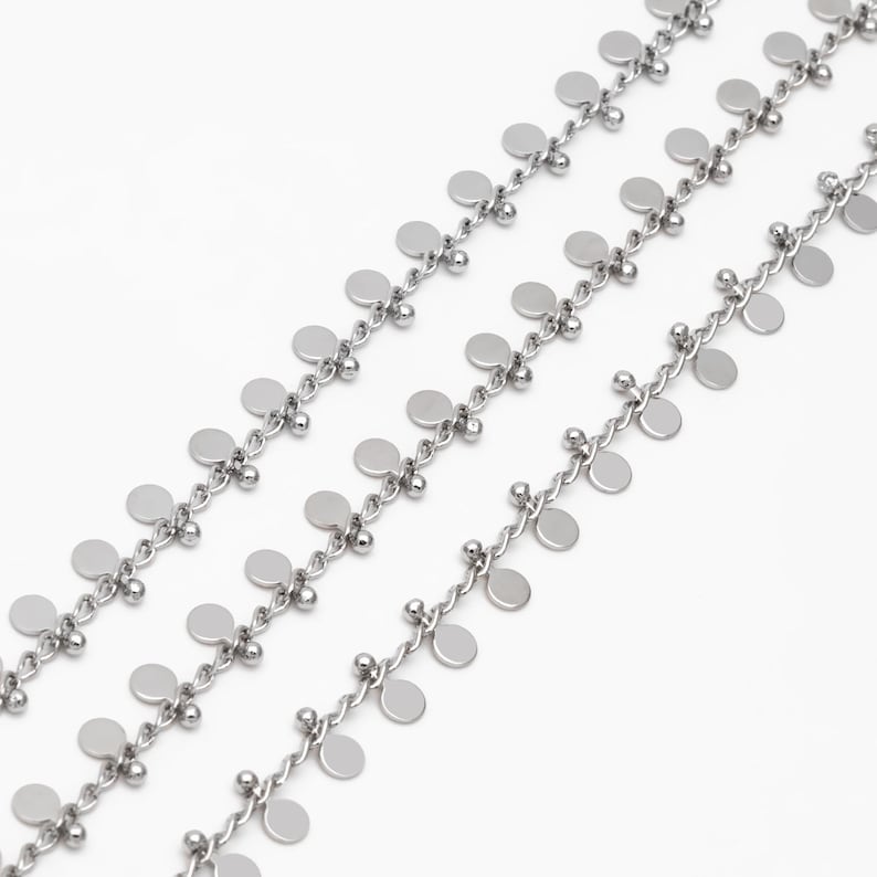 May include: A silver chain necklace with multiple strands of small round discs hanging from it.