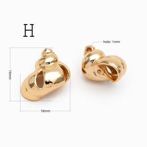 May include: Two gold-colored metal shell charms labeled H. The charms measure 19mm in height and 18mm in width, featuring a 1mm hole for attachment. The smooth, reflective surface mimics the spiral shape of a seashell in a polished finish.
