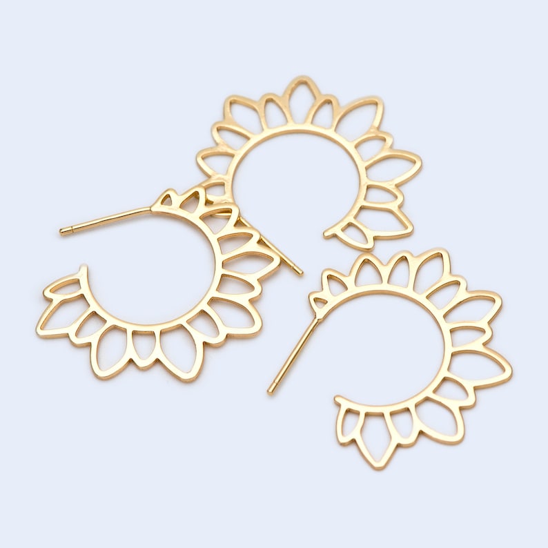 Puede incluir: Tres pendientes de aro dorados con un delicado dise&ntilde;o floral. Los pendientes est&aacute;n hechos de metal y tienen una forma circular.