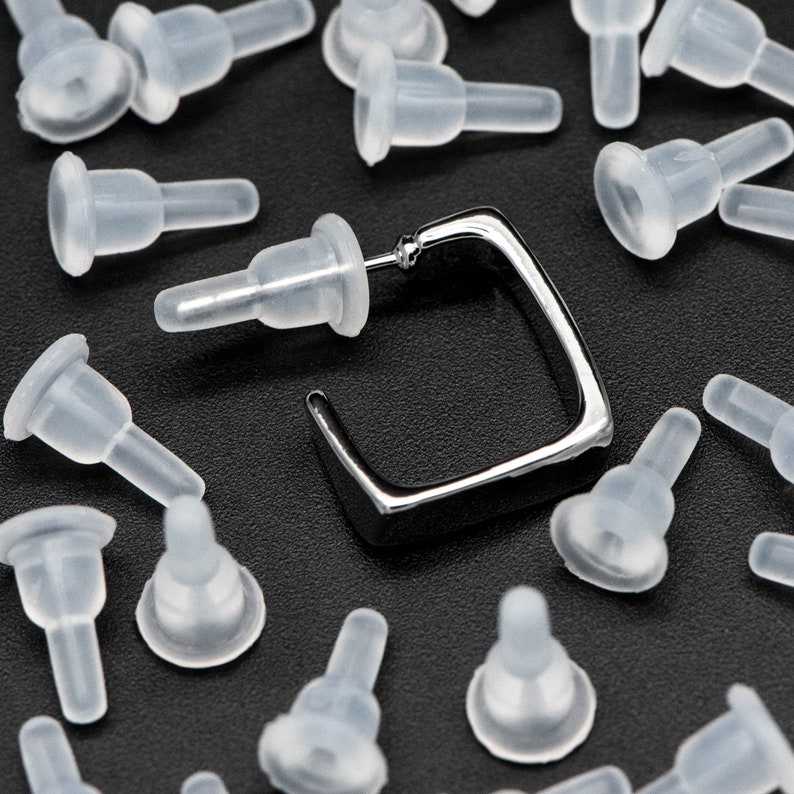 May include: A silver square earring with a post and a variety of clear silicone earring backs.