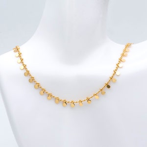 May include: A gold necklace featuring a fine chain with small round charms dangling from it.