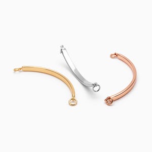 May include: Three metal bracelet extender clasps in silver, gold, and rose gold. Each clasp is a curved bar with a small ring at each end.