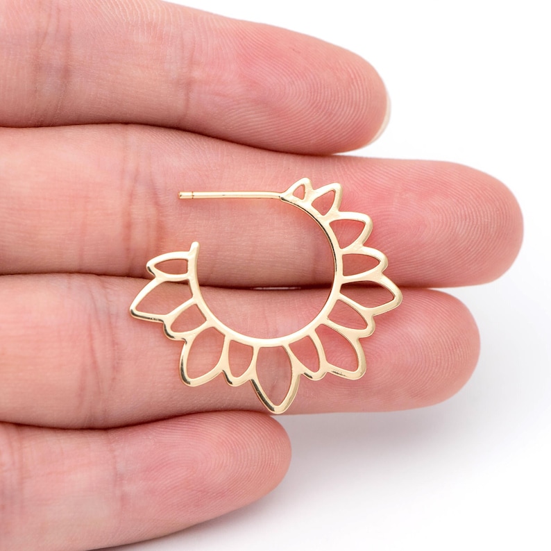 Puede incluir: Pendientes de aro dorados con un delicado dise&ntilde;o de sol. Los pendientes est&aacute;n hechos de un metal fino y calado y tienen una forma ligeramente redondeada.
