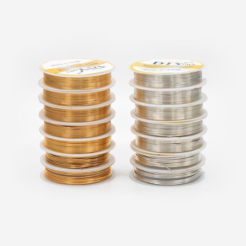 May include: Two stacks of spools of wire for jewelry making. One stack is gold wire and the other is silver wire. Each spool is labeled "DIY Jewelry Making Wire, Size 0.2mm".