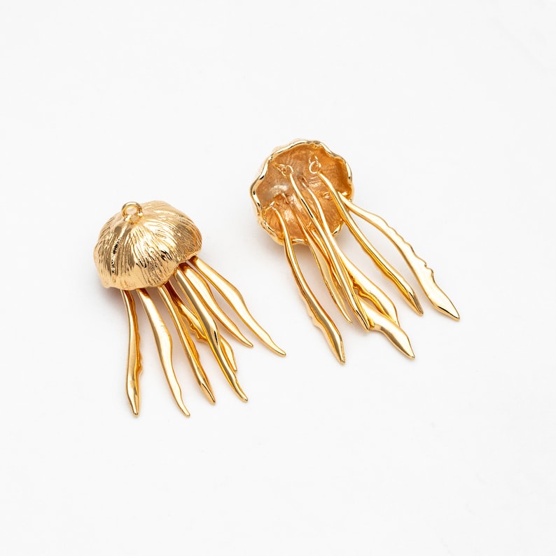 May include: A pair of gold-tone jellyfish earrings with detailed, textured bodies and dangling tentacles.