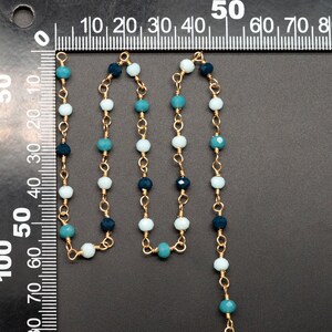 May include: A gold chain necklace with blue and white glass beads. The necklace is approximately 50 inches long.