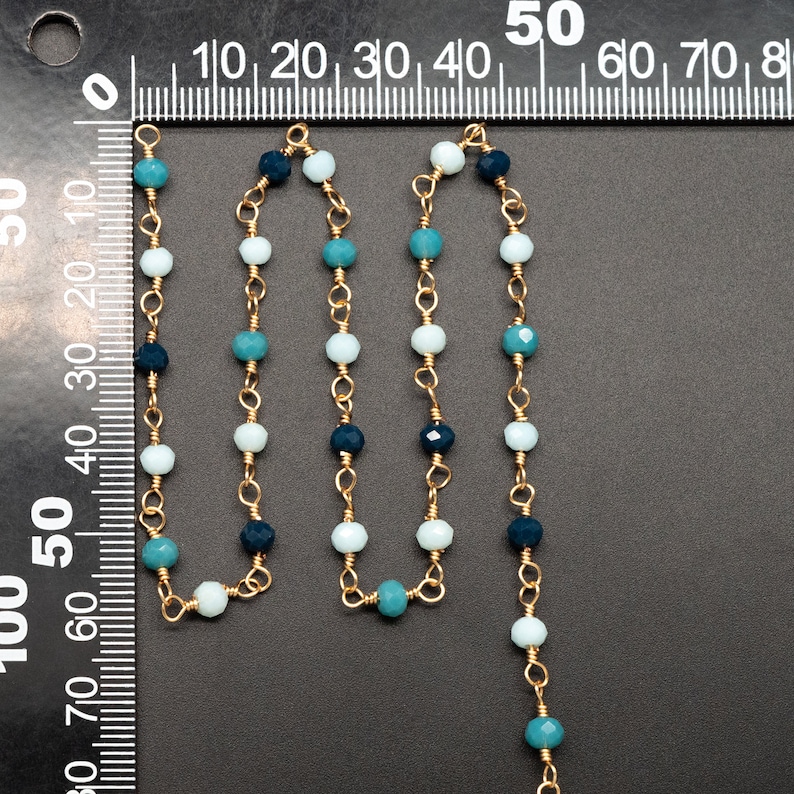 May include: A gold chain necklace with blue and white glass beads. The necklace is approximately 50 inches long.