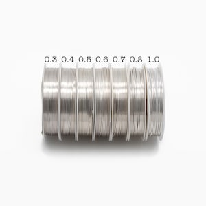 May include: A set of seven spools of silver wire, each labeled with a different gauge: 0.3, 0.4, 0.5, 0.6, 0.7, 0.8, and 1.0.