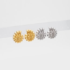 May include: A pair of gold and silver nautilus shell earrings. The earrings are displayed on a white background.