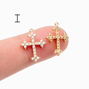 Pu&ograve; includere: Due ciondoli a forma di croce color oro. Una croce &egrave; incastonata con piccole pietre preziose trasparenti. L'altra croce ha un design strutturato. Entrambe le croci hanno un piccolo anello nella parte superiore per essere appese. La lettera "I" &egrave; nell'angolo in alto a sinistra.