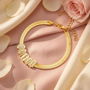 May include: A gold-toned herringbone chain bracelet featuring five rectangular charms, each engraved with a name: Sophia, Payton, Angela, Christian, and Valentine. The charms are accented with small clear stones and include a lobster clasp closure.