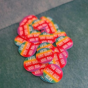 May include: A pile of colorful round stickers with the text "You look super cute today" in white lettering. The stickers have a rainbow gradient background.