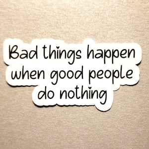 May include: White sticker with black text that reads "Bad things happen when good people do nothing." The sticker has a rounded, cloud-like shape and is set against a neutral background.