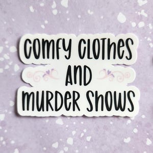 May include: White sticker with black text that reads "Comfy clothes and murder shows".