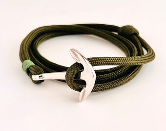 Puede incluir: Una pulsera de paracord verde con un dije de ancla de plata.