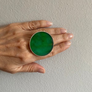 Op de afbeelding: Een grote, ronde, groene statement ring met een zilveren zetting.