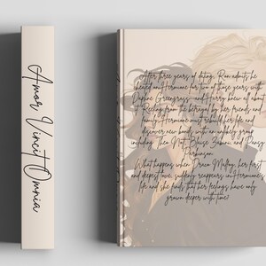 May include: A book with a beige spine featuring the words "Amor Vincit Omnia" in black script. The book cover displays a side profile of a person with text describing a story of betrayal and rediscovery.