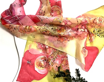 May include: A yellow and pink silk scarf with a floral pattern and a black Chinese character. The scarf is draped over a white mannequin.