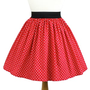 May include: A red skirt with white polka dots and a black waistband. The skirt is on a white mannequin.