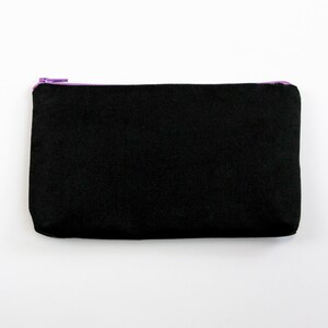 May include: A black zippered pouch with a purple zipper.