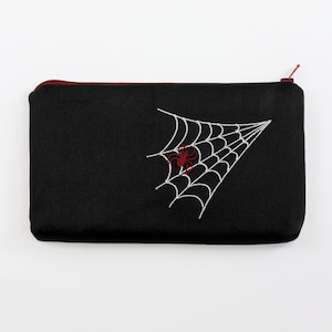 May include: Black zippered pouch with a white embroidered spider web and a red spider in the center.