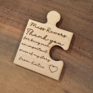 May include: A wooden jigsaw piece with the text "Miss Rivers Thank you for being such an important piece of my story from Katie" and a small heart.