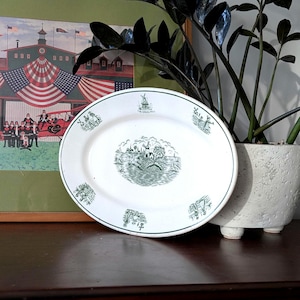 May include: White oval serving platter with a green border and detailed green illustrations. The center features a landscape scene, and smaller scenes are spaced around the rim. The text "THE GREEN MAN" is visible.