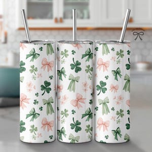 Peut inclure: Trois gobelets en acier inoxydable avec un fond blanc et un motif de trèfles verts et de nœuds roses.