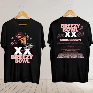 May include: Black t-shirt with a pink graphic featuring the text "XX BREEZY BOWL" and an image of Chris Brown. The back of the shirt displays tour dates for Europe and North America.