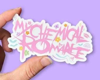 May include: A pink sticker with the words "My Chemical Romance" in a stylized font. The sticker is decorated with small flowers, butterflies, and other whimsical shapes. The sticker is held between two fingers against a purple background.