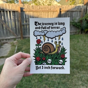 May include: A snail with a yellow shell crawls through a field of green grass and red flowers. The sky is gray and stormy with lightning and rain. The text reads "The journey is long and full of terror. Yet I inch forward."