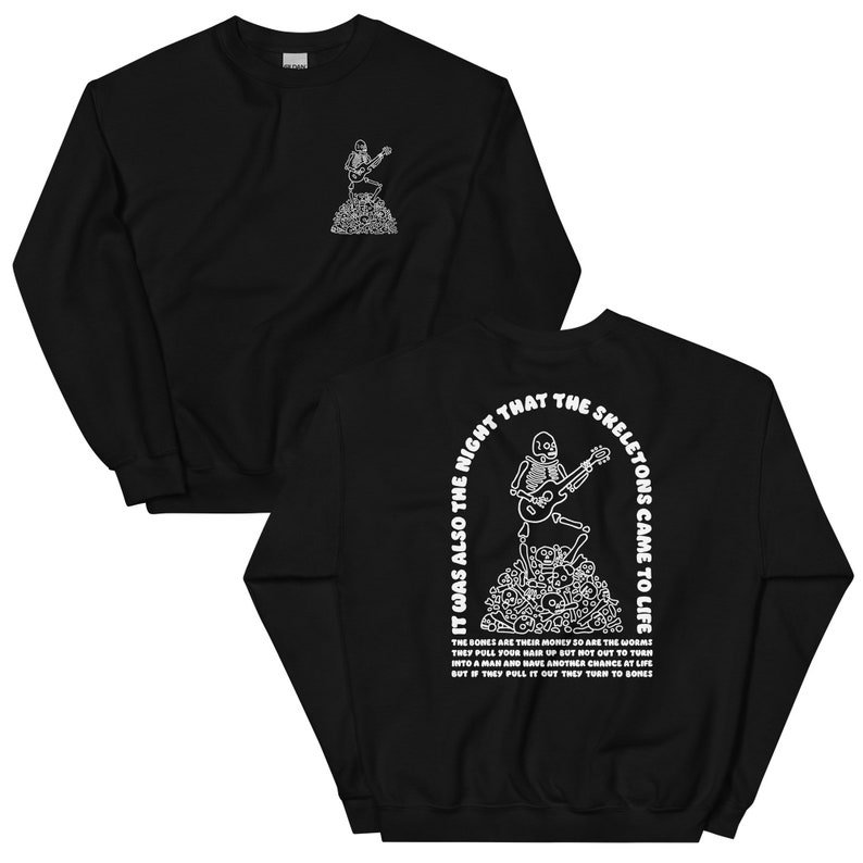 Może przedstawiać: Czarny sweter z białym nadrukiem graficznym przedstawiającym szkielet grający na gitarze na stercie kości. Tekst "It was also the night that the skeletons came to life" jest nadrukowany białym łukiem wok&oacute;ł szkieletu. Kości są ich pieniędzmi, tak jak robaki, ciągną twoje włosy do g&oacute;ry, ale nie na zewnątrz, abyś m&oacute;gł się zmienić w mężczyznę i mieć kolejną szansę na życie, ale jeśli je wyciągną, zamieniają się w kości.
