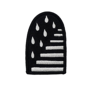 Pode incluir: Patch bordado preto e branco com um design de gotas de chuva caindo sobre um padrão listrado.