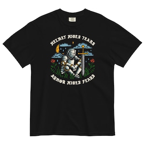 Puede incluir: Camiseta negra con un gráfico de un caballero con armadura sentado con una espada. El texto "Helmet hides tears, Armor hides fears" está impreso en la camiseta.