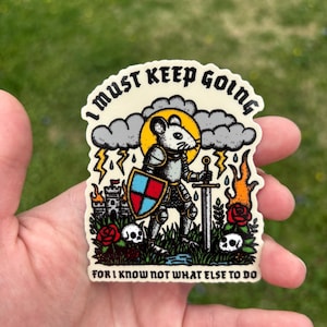Può includere: Un adesivo bianco con un cavaliere topo dei cartoni animati che tiene una spada e uno scudo. Il topo è in piedi in un campo con un castello sullo sfondo. L'adesivo dice "Devo andare avanti perché non so cosa altro fare."