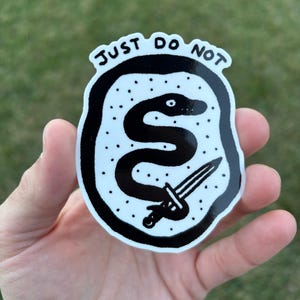 May include: Black and white sticker with a snake and a dagger inside a circle. The text "JUST DO NOT" is written around the circle.