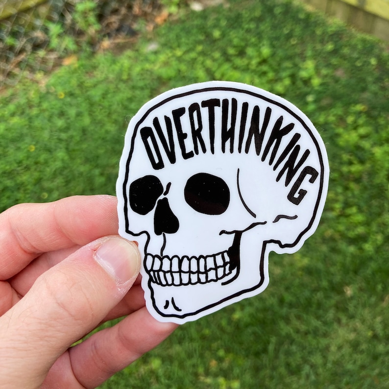 Op de afbeelding: Witte schedelsticker met het woord "Overthinking" eromheen geschreven.