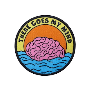 May include: Embroidered patch with a circular design. The patch features a pink brain floating in blue water, set against an orange sun. The text "THERE GOES MY MIND" is in black, arched around the top edge of the patch.